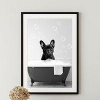 Framed artwork of a dog in a bathtub with bubbles on a wall above a wooden console table.