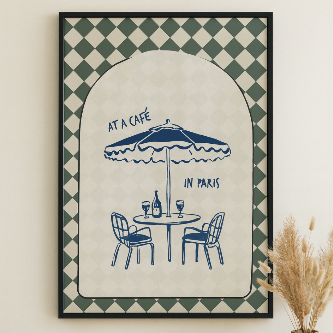Framed artwork with 'At a Café in Paris' design on a wall above a wooden table.
