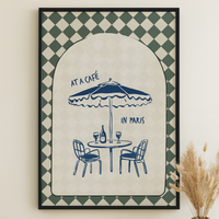 Framed artwork with 'At a Café in Paris' design on a wall above a wooden table.